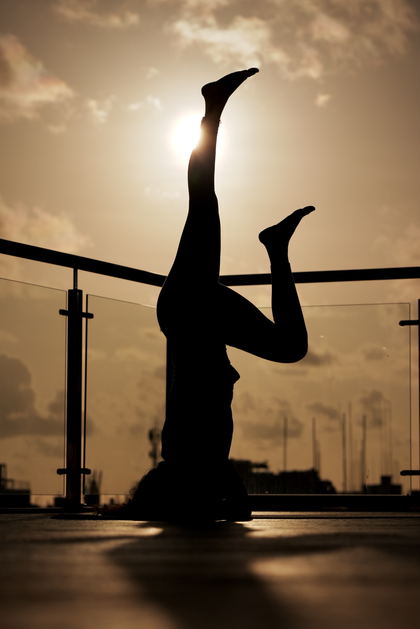 Zey in headstand silhouette with the sun behind her foot